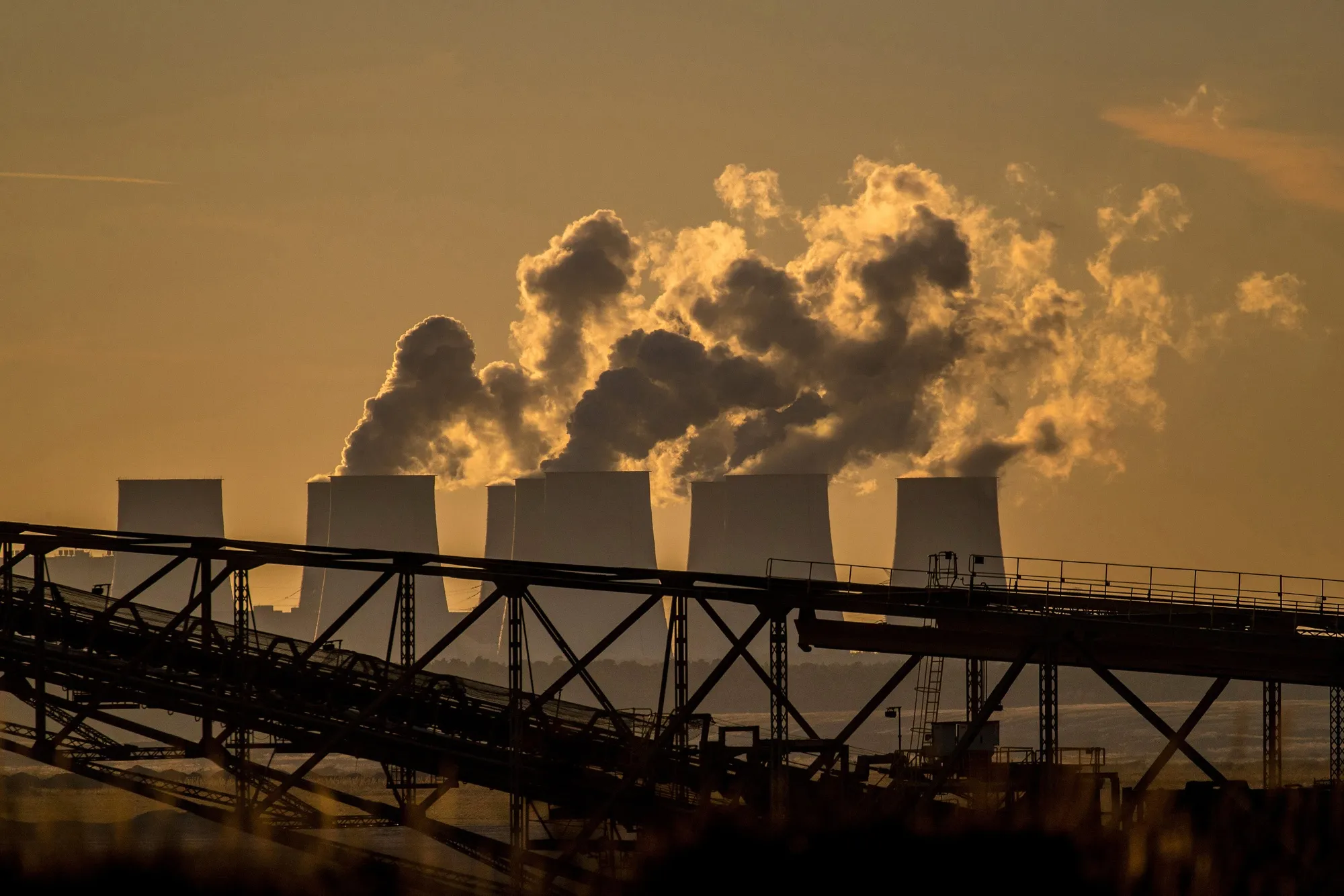 A&nbsp;lignite-fired power station beyond a conveyor bridge at the open-cast lignite mine in Jaenschwalde, Germany.