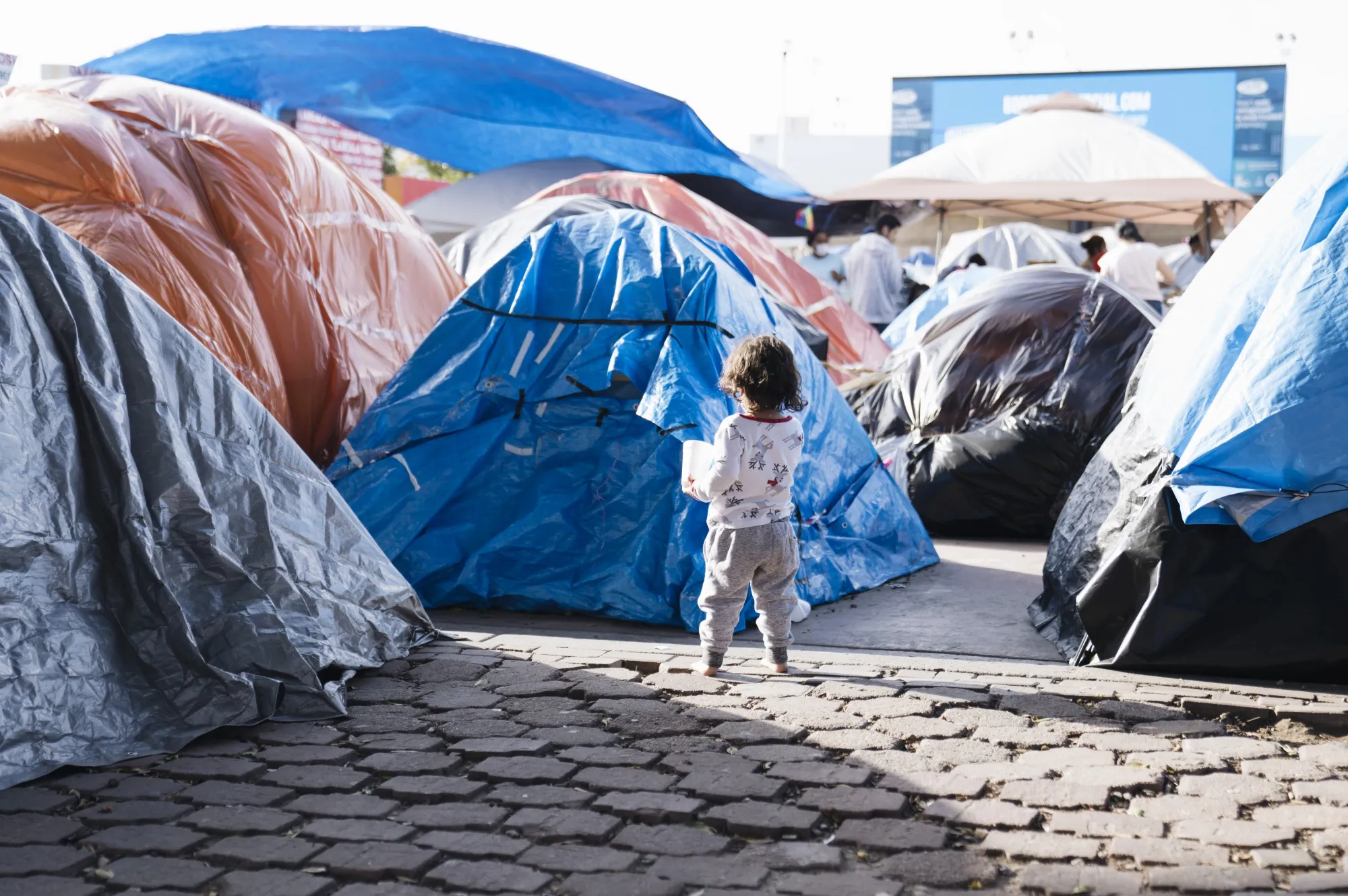 A child walks past tents at a makeshift housing camp for migrants seeking asylum hearings in Tijuana, Mexico, on March. 21.