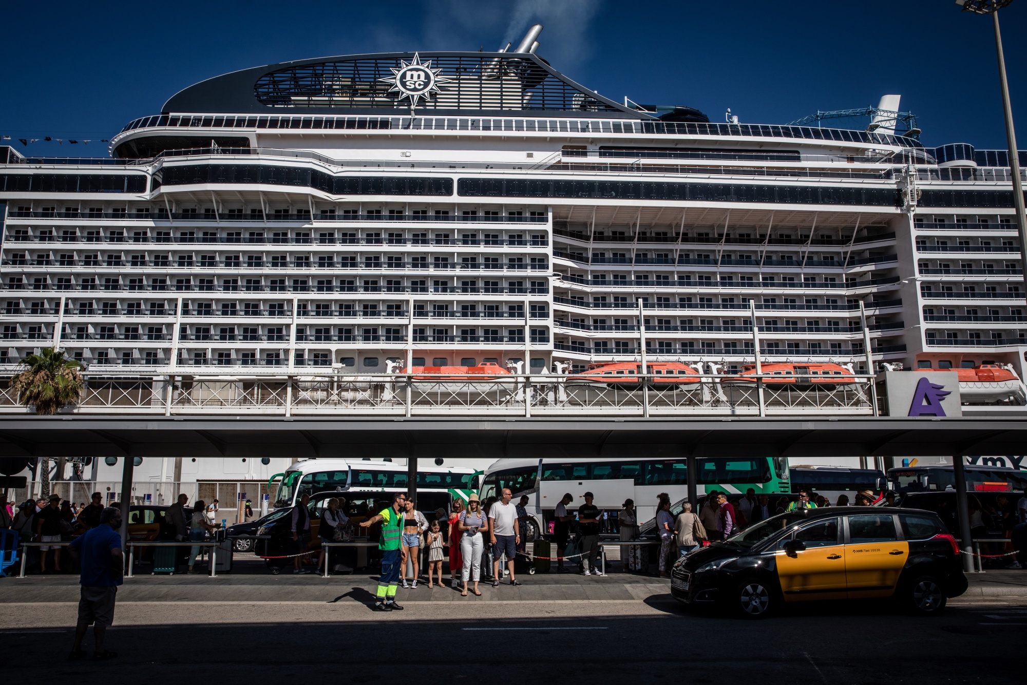 Tourists queue for onward travel at a cruise terminal in Barcelona.