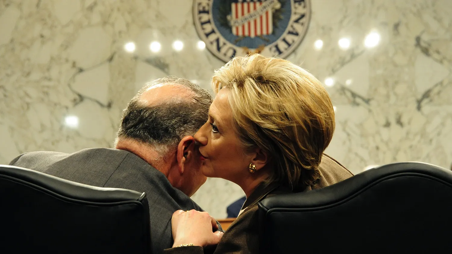Hillary Clinton whispers to Senator Charles Schumer (back to camera) during nomination hearings before the Senate Foreign Relations Committee on Jan. 13, 2009, in Washington.
