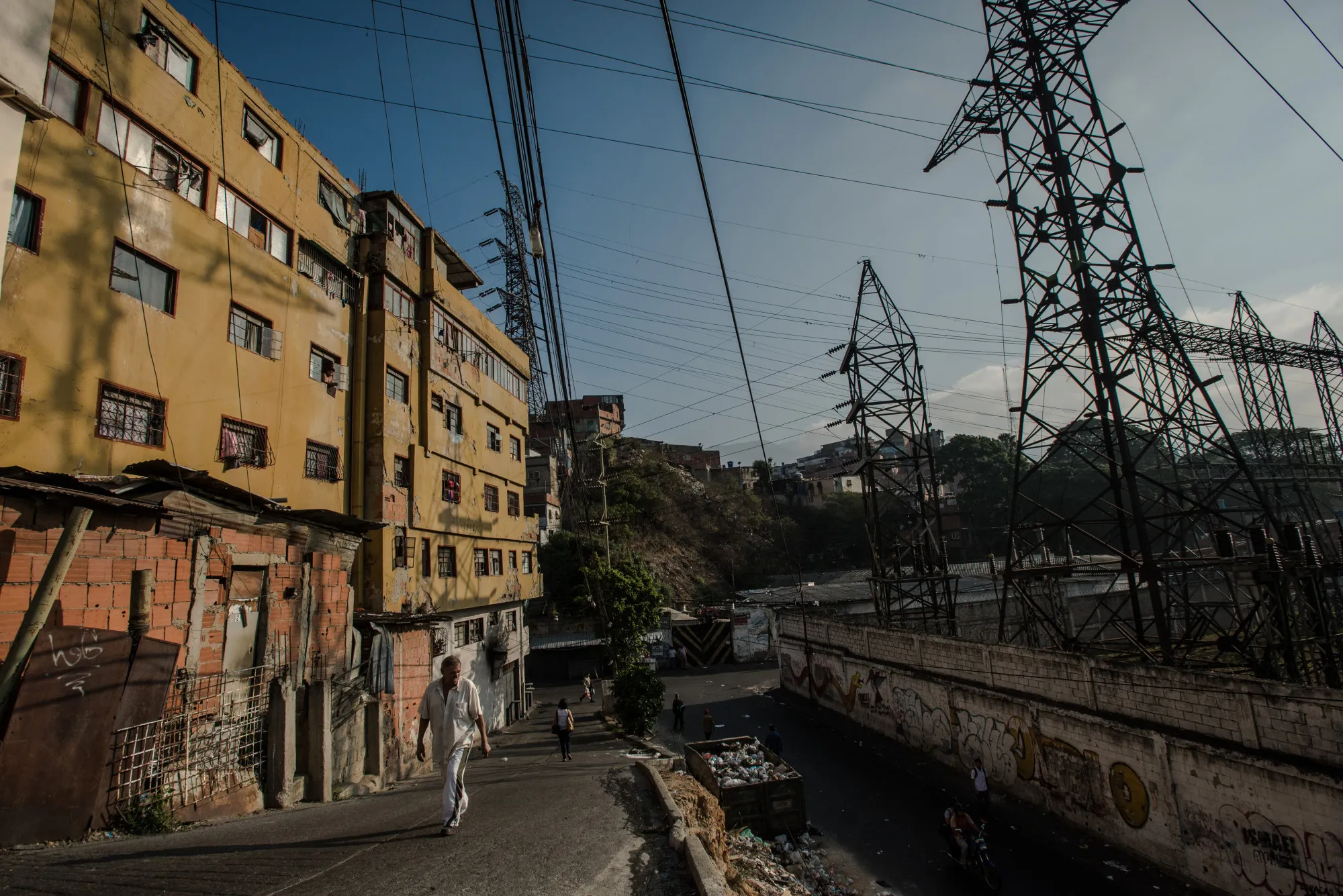 People walk past an electrical substation run by Corpoelec,&nbsp;in a slum in Caracas, Venezuela.