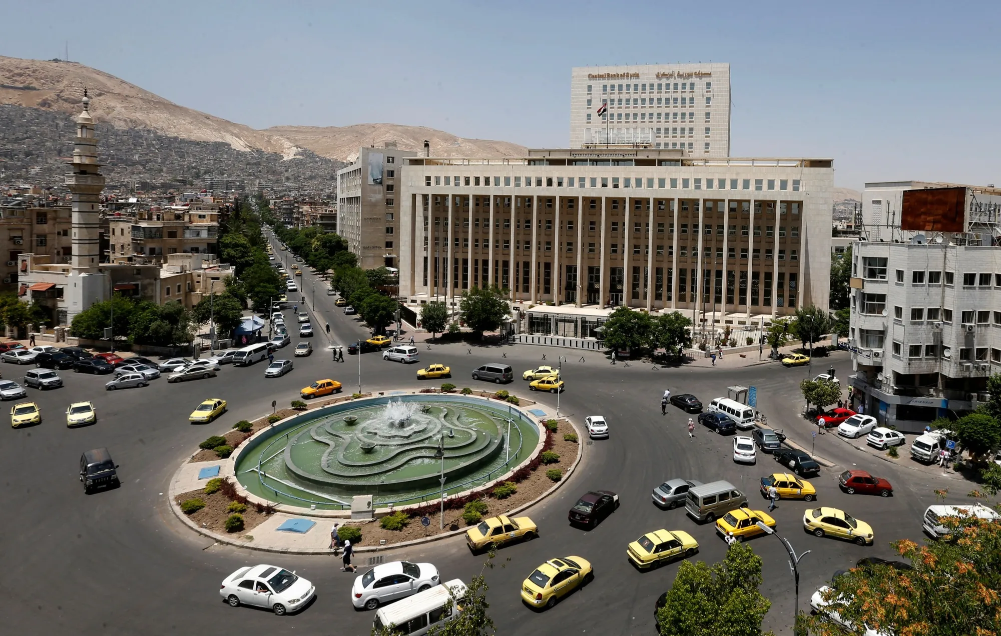Vehicles drive along the roundabout past the Central bank of Syria in Damascus.