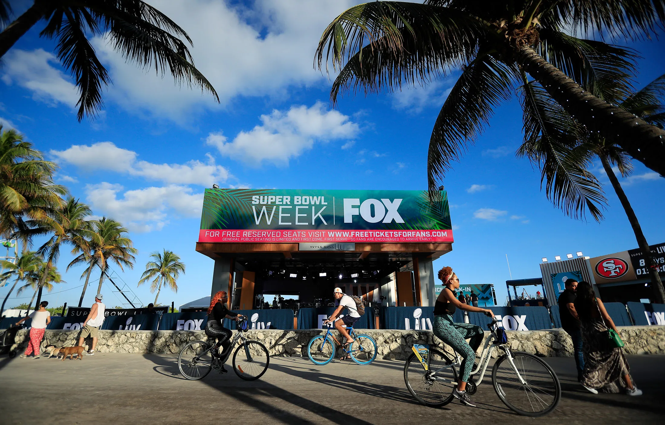 Cyclists ride past the FOX Sports South Beach studio compound prior to the Super Bowl.