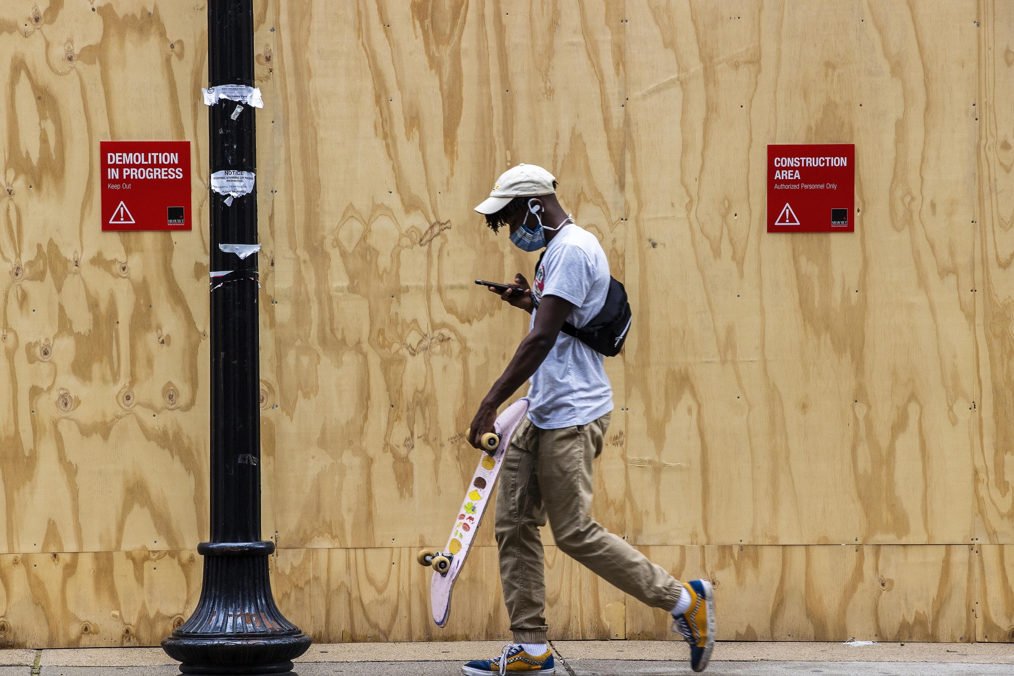 A young skateboarder walks though a boarded up Park Square in Boston in September.