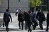 Morning commuters walk across a road in Tokyo.