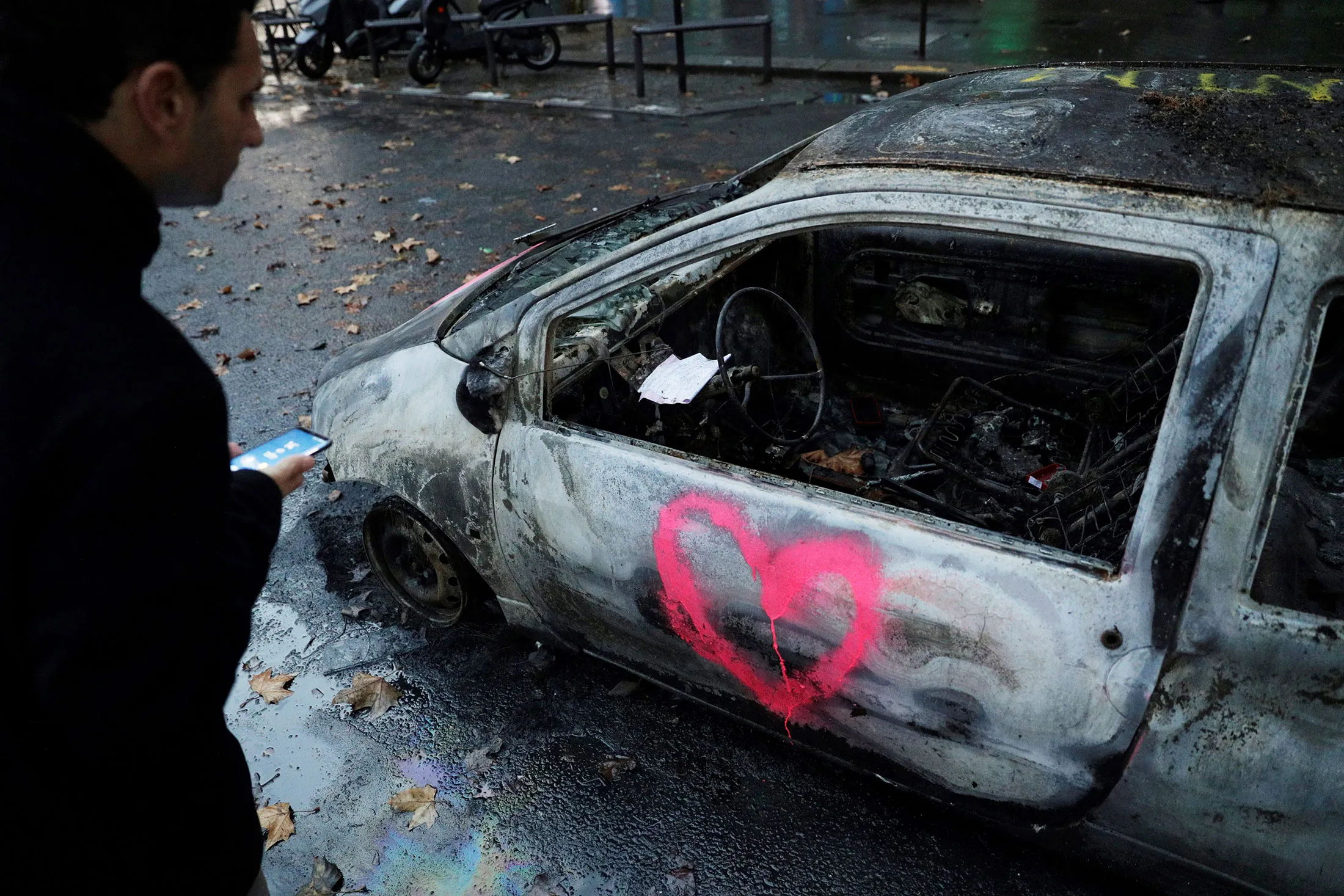 A man looks at a burned out car following protests in Paris on Dec. 2.