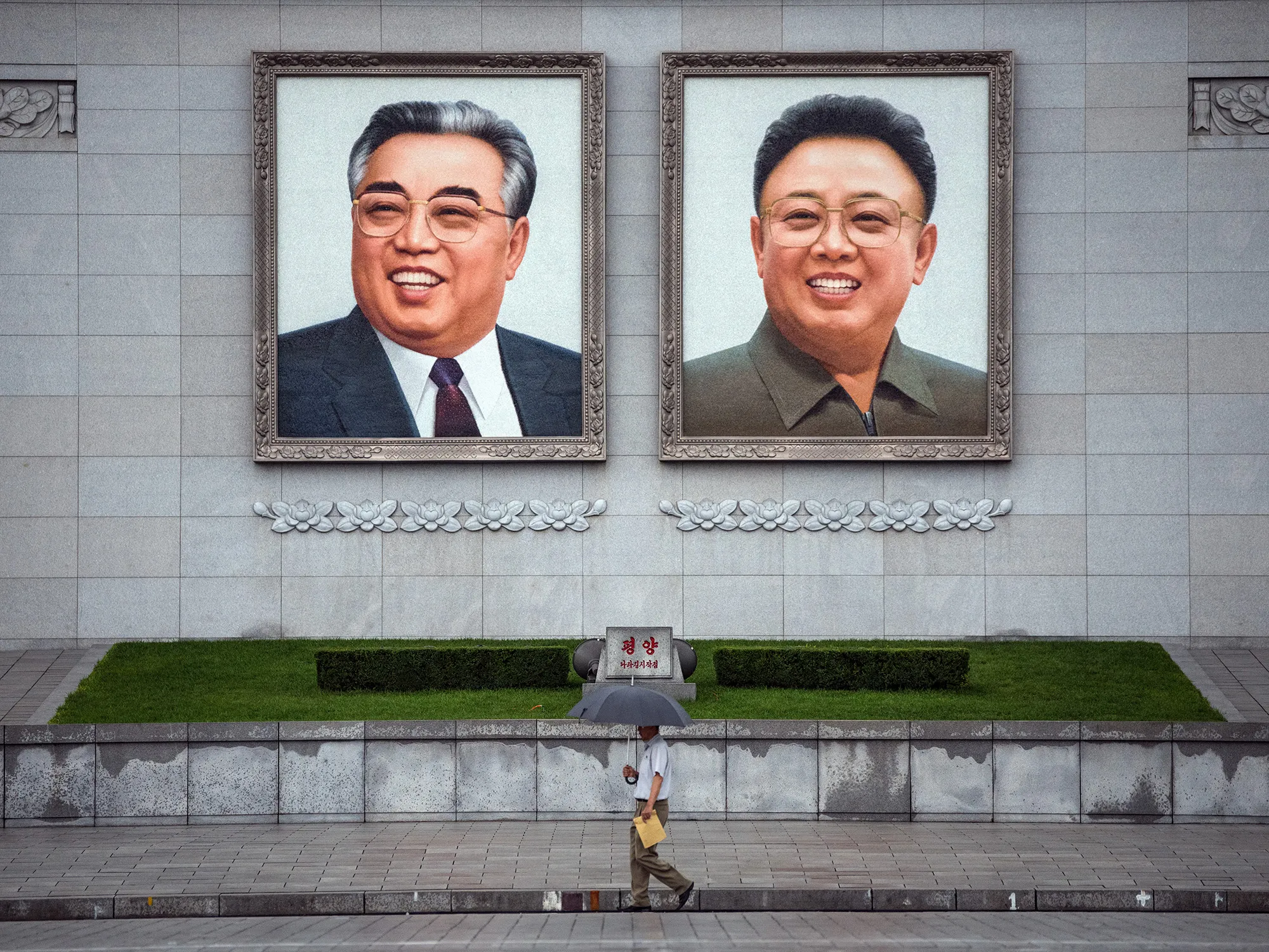 A person walks beneath portraits of Kim Il-sung and Kim Jong-il displayed in Kim Il-sung Square in Pyongyang.