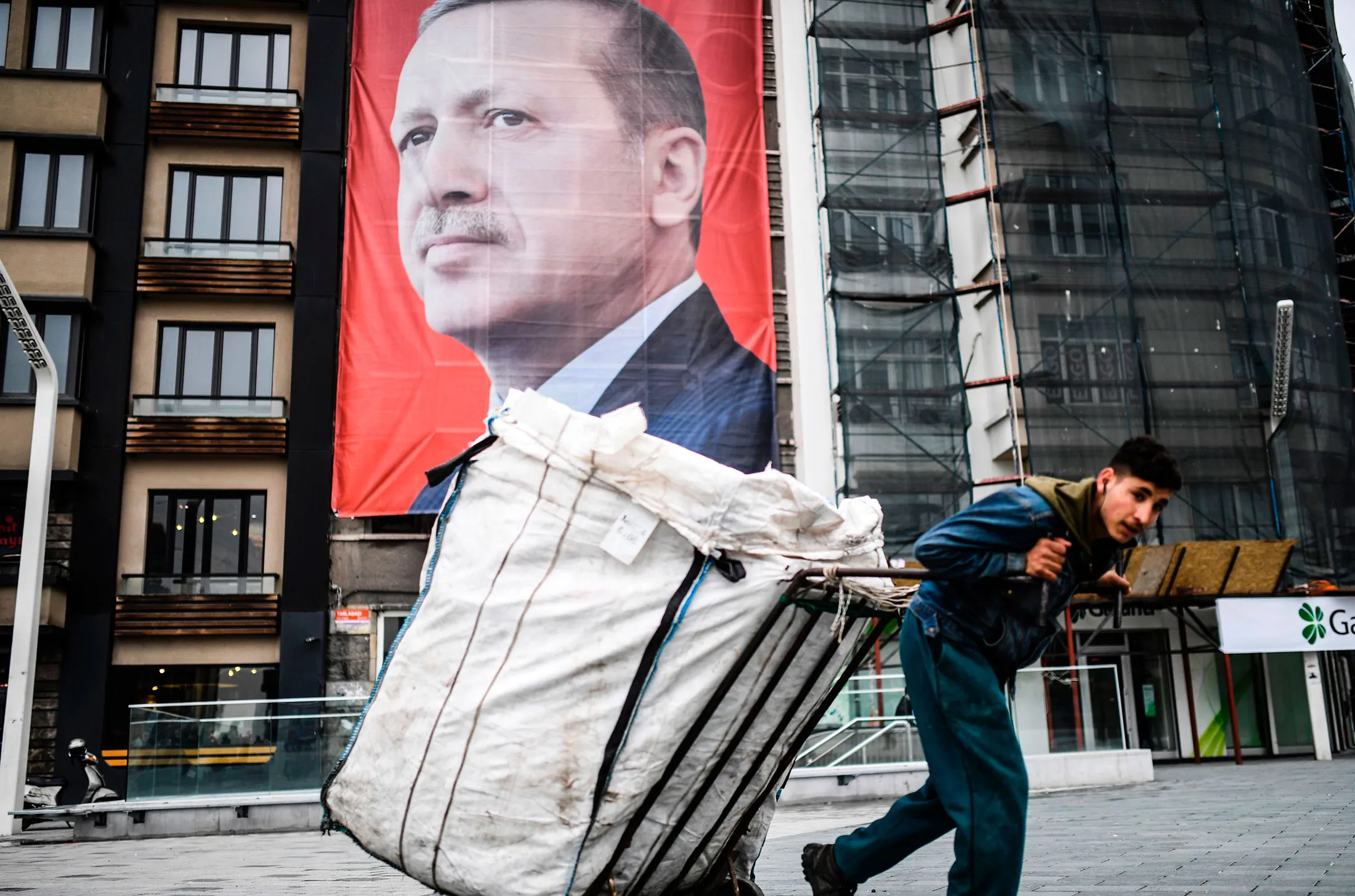 A man pulls a cart in front of a portrait of Recep Tayyip Erdogan in Istanbul. 