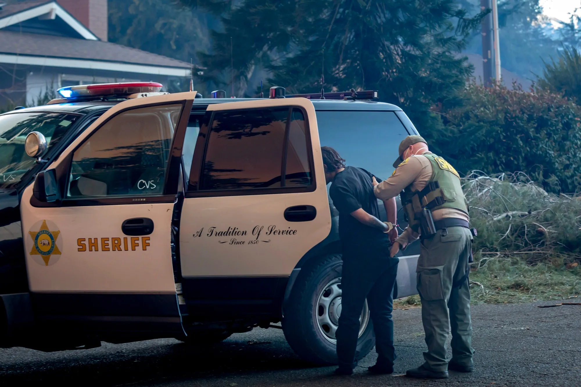 An alleged looter is arrested and taken away in handcuffs during the Eaton Fire in Altadena on Jan. 8.