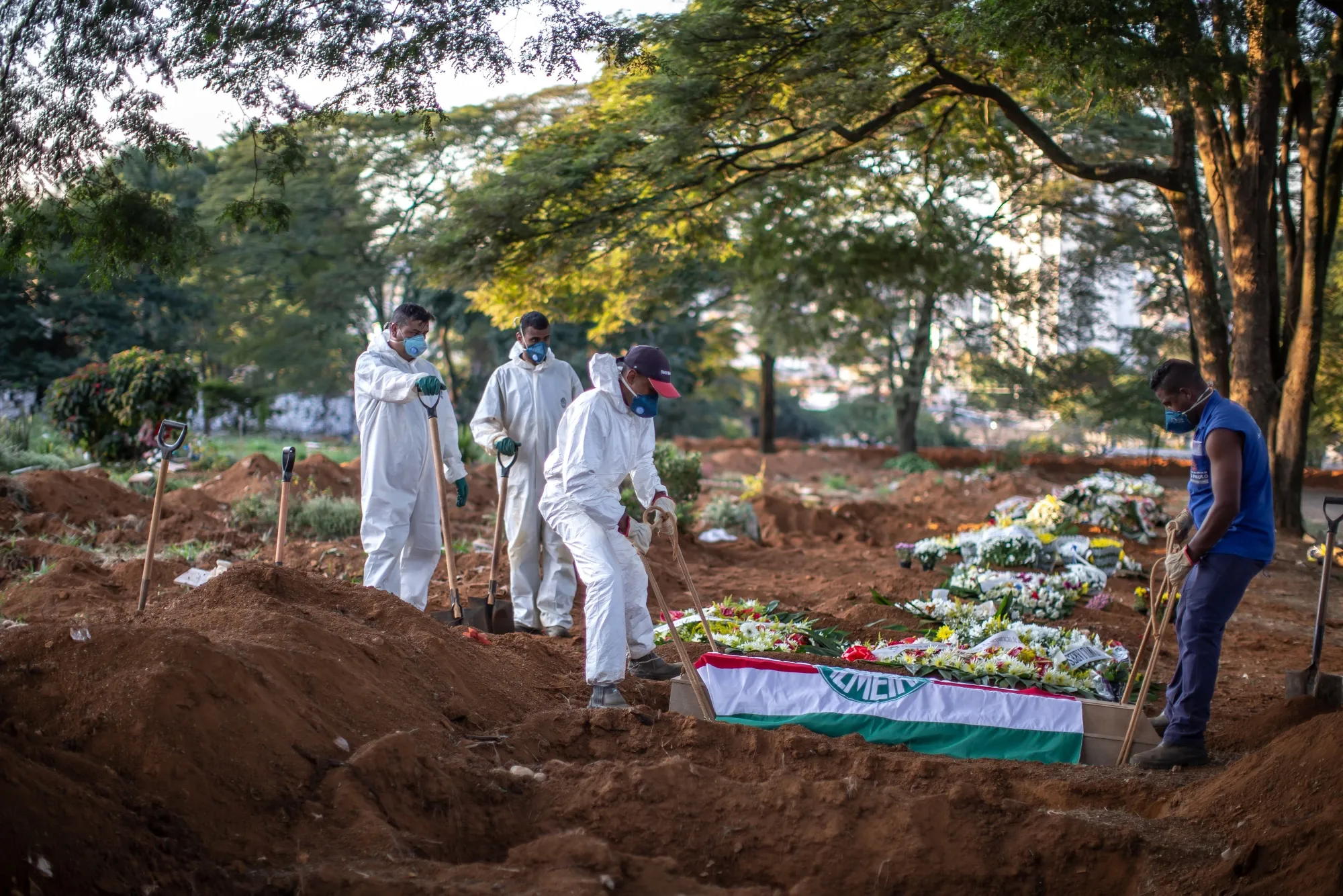 Workers wearing protective gear lower the casket of a Covid-19 victim at the Vila Formosa cemetery in Sao Paulo, Brazil, on Wednesday, April 29, 2020. 