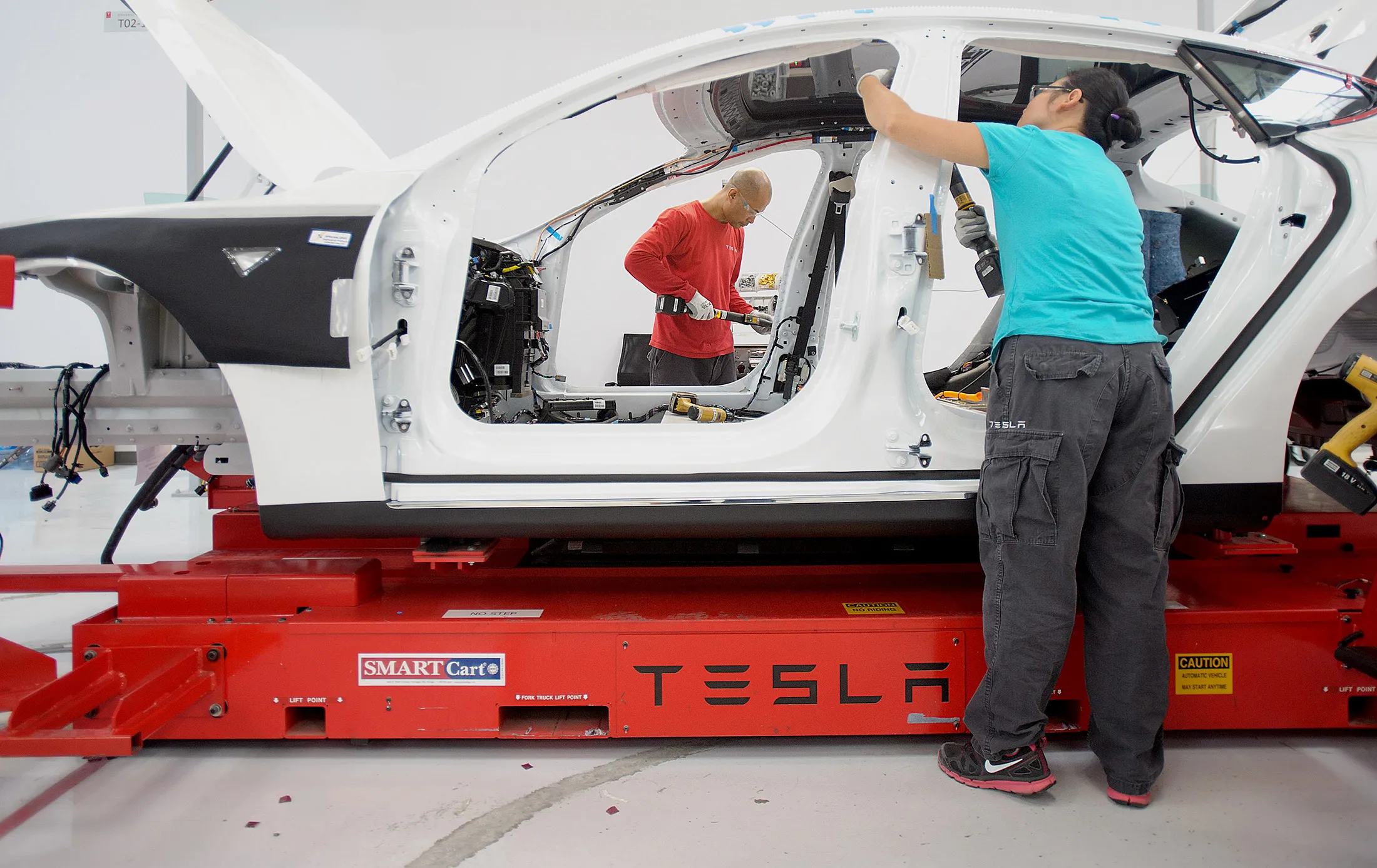 Workers add seat belts to a Telsa Motor Inc. Model S sedan at the company's assembly plant in Fremont, California.

