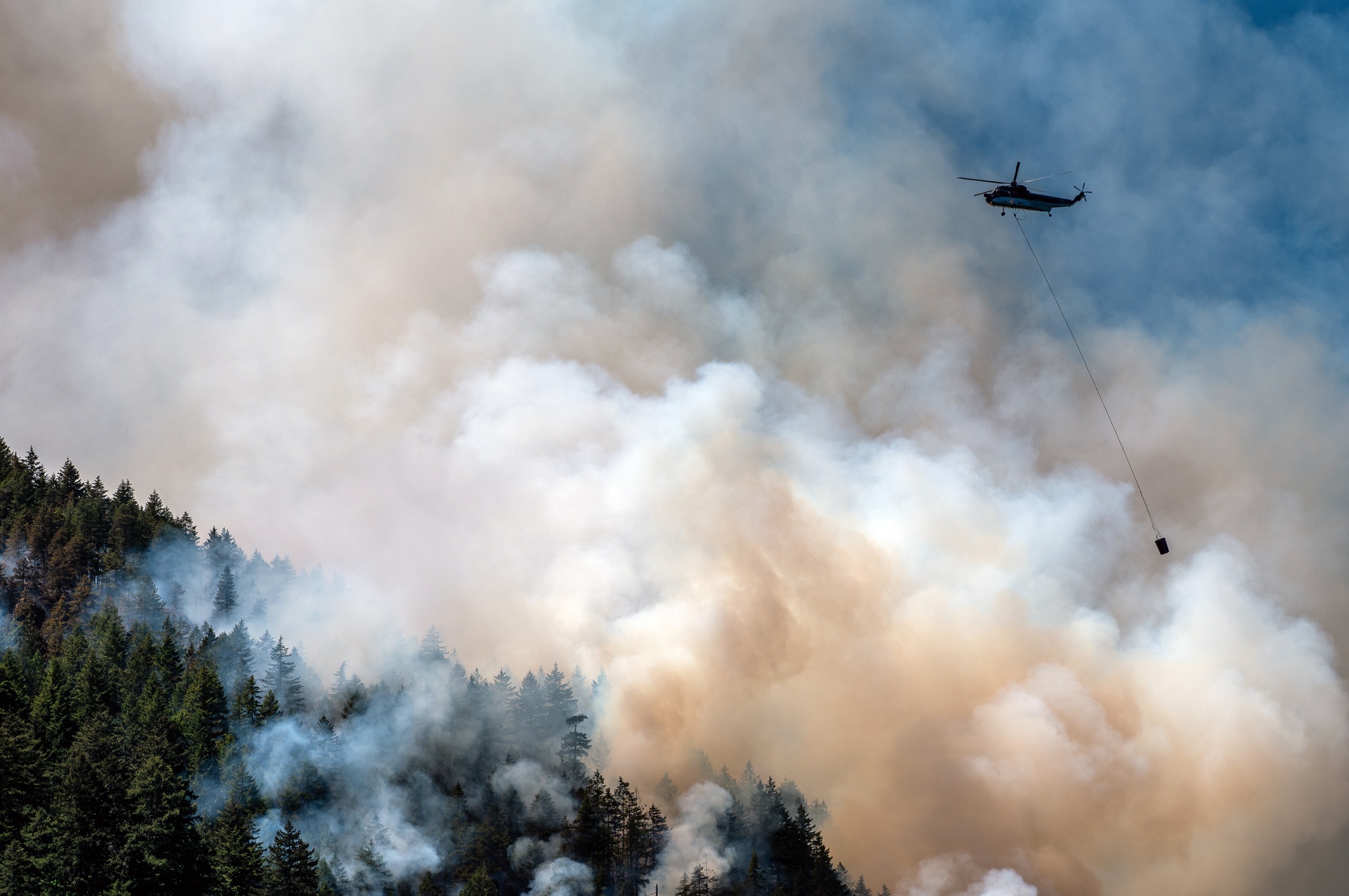 A helicopter waterbomber flies above the Cameron Bluffs wildfire near Port Alberni, British Columbia, on&nbsp;June 6.&nbsp;