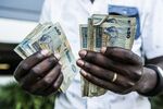 A man counts out Zambian kwacha 50 denomination banknotes.&nbsp;