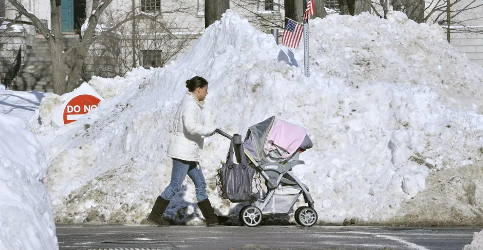 Forced into the street by blocked sidewalks, a woman pushes a stroller past piles of snow outside Massachusetts General Hospital in Boston.