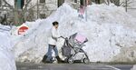 Forced into the street by blocked sidewalks, a woman pushes a stroller past piles of snow outside Massachusetts General Hospital in Boston.
