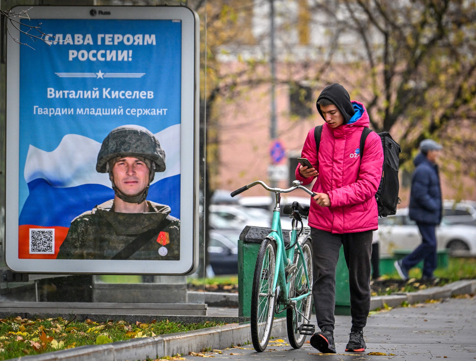 A courier walks past a poster of a Russian soldier with the slogan 'Glory to the Heroes of Russia'&nbsp;in Moscow.&nbsp;Officials have warned that the call-up announced in September and the exodus of hundreds of thousands more Russians that followed are worsening an already-severe shortage of workers.