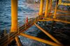 A worker looks out to sea from a low walkway aboard an offshore oil platform in the Persian Gulf's Salman Oil Field, operated by the National Iranian Offshore Oil Co., near Lavan island, Iran.