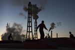 Men walk in front of smoke rising from chimneys at factories at dusk in Kamisu, Ibaraki, Japan. 