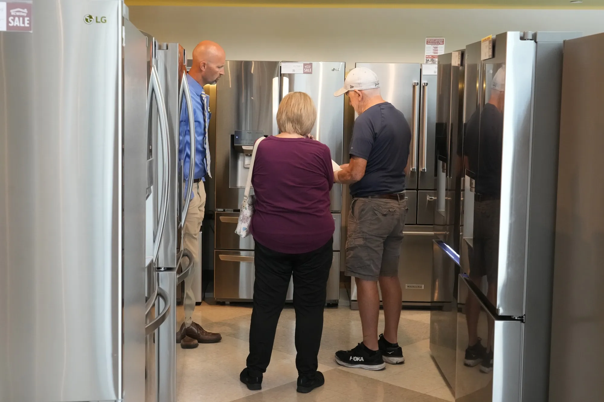 A salesman shows customers refrigerators at a home furnishings store in Orem, Utah.