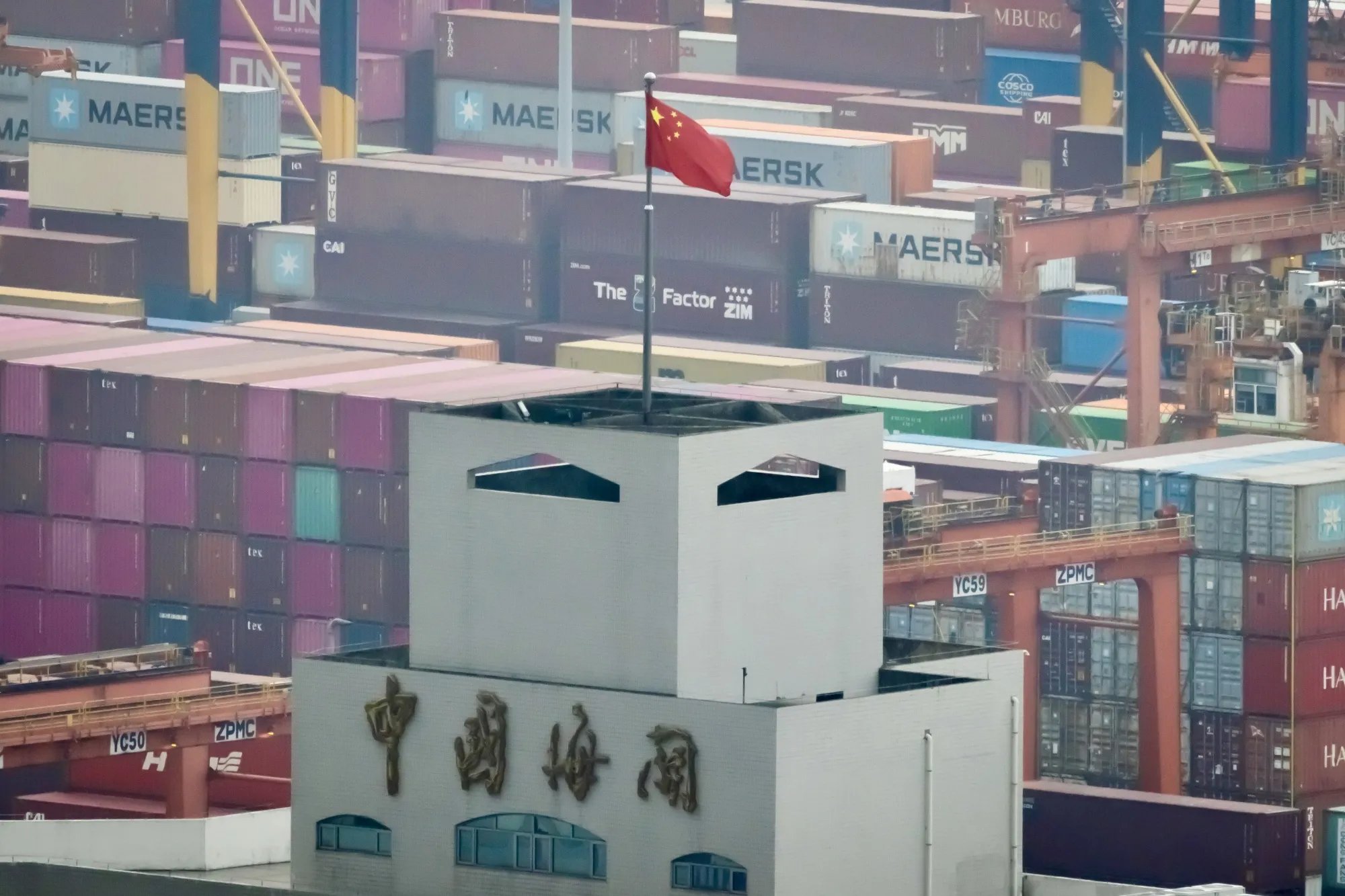 A Chinese national flag flies atop a China customs building at Yantian International Container Terminals. The nation has responded to US tariff threats by increasing its exports elsewhere.