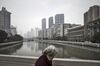 A woman walks over a bridge overlooking Suzhou Creek in Shanghai, China.