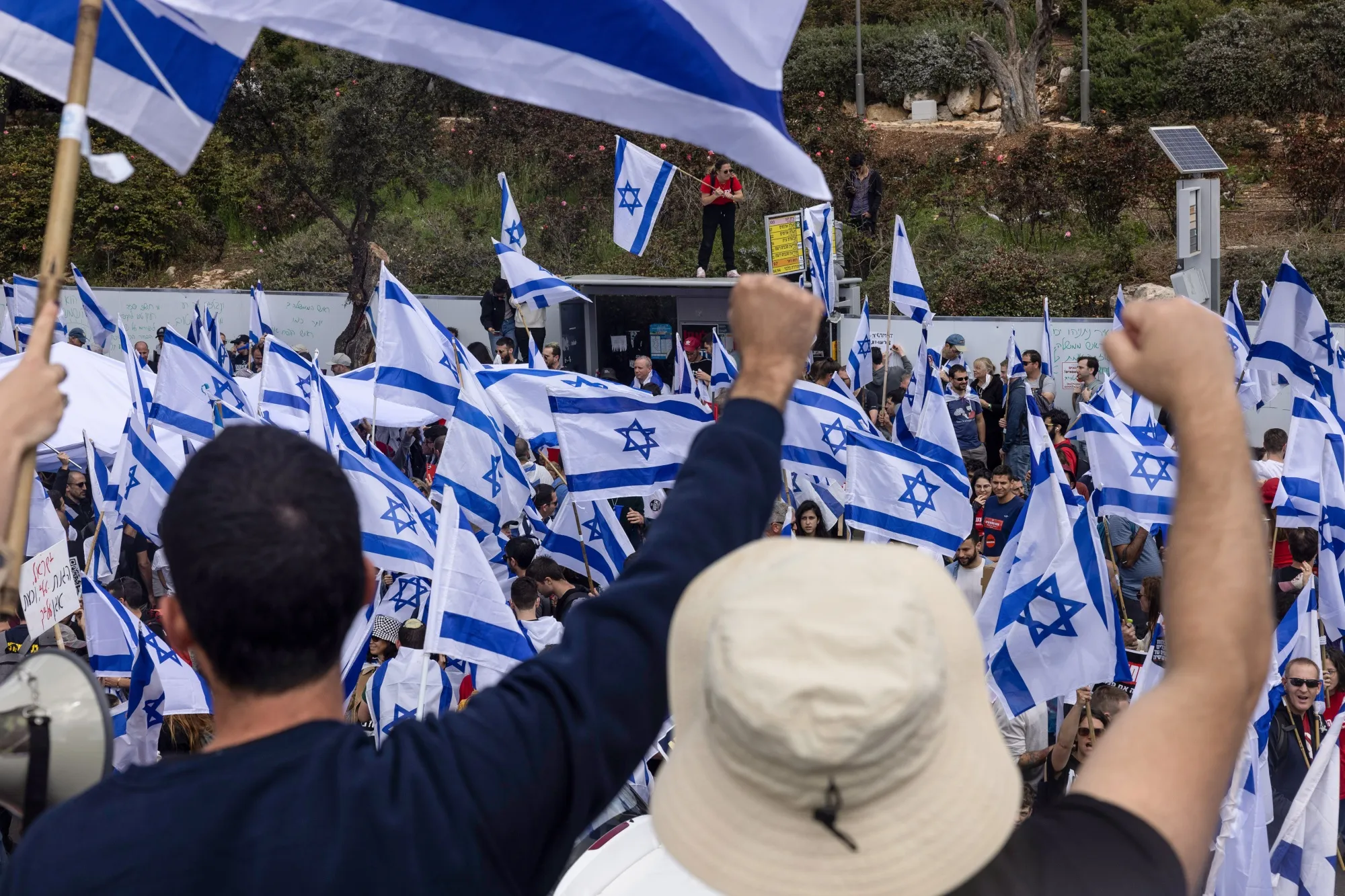Demonstrators wave Israeli national flags during a protest outside Israel's parliament.