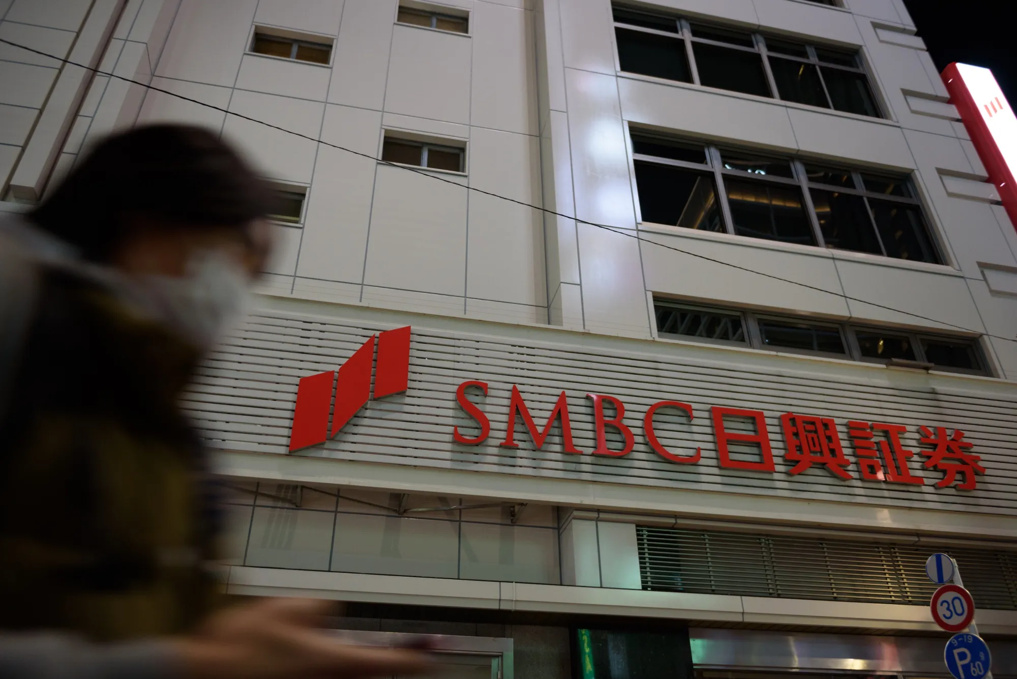 A pedestrian walks past a branch of SMBC Nikko Securities Inc. in Tokyo.