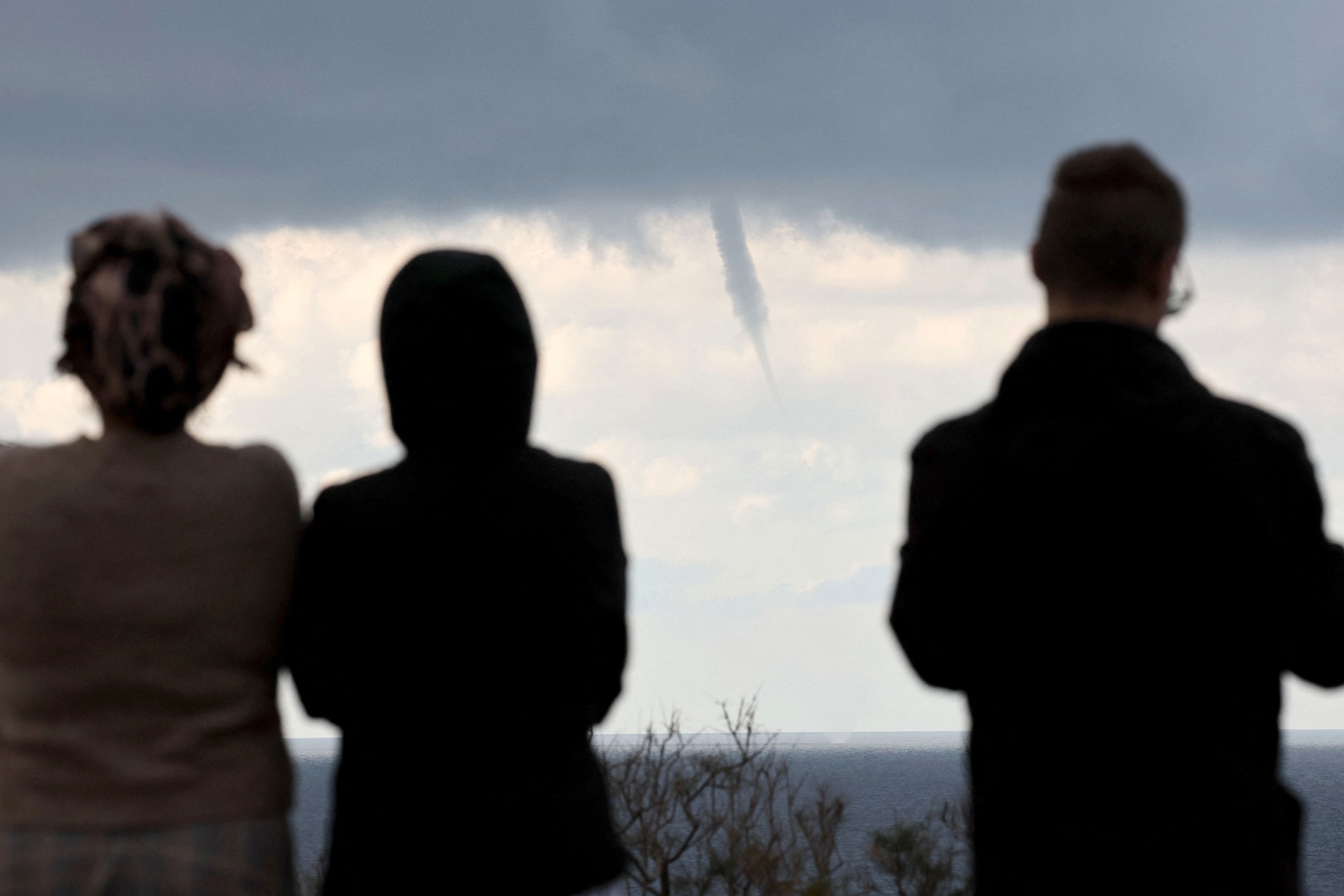 People watch a waterspout form over the Mediterranean Sea on Jan. 7.