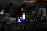 A worker looks at his mobile phone while using a rechargeable LED lantern to illuminate inside a pharmacy at the Sinnoville Centre after its electricity supply was cut off by the City of Tshwane municipality&nbsp;in Pretoria, South Africa, in February.
