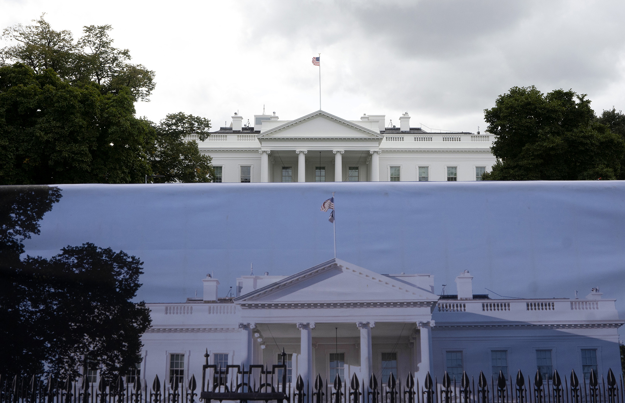 A photograph of the White House is displayed in front of the building in Washington D.C.