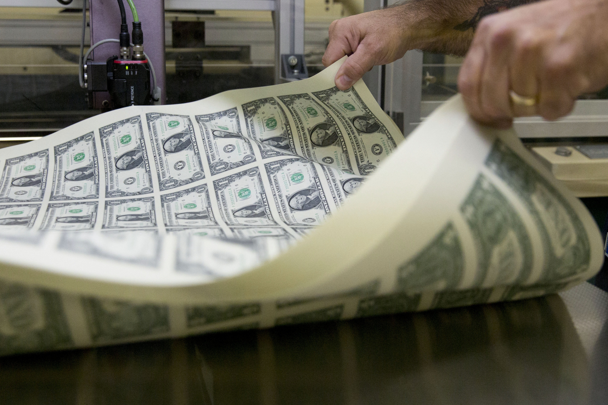 A pressman aerates a stack of&nbsp;uncut sheets of $1 dollar notes at the U.S. Bureau of Engraving and Printing in Washington, D.C.