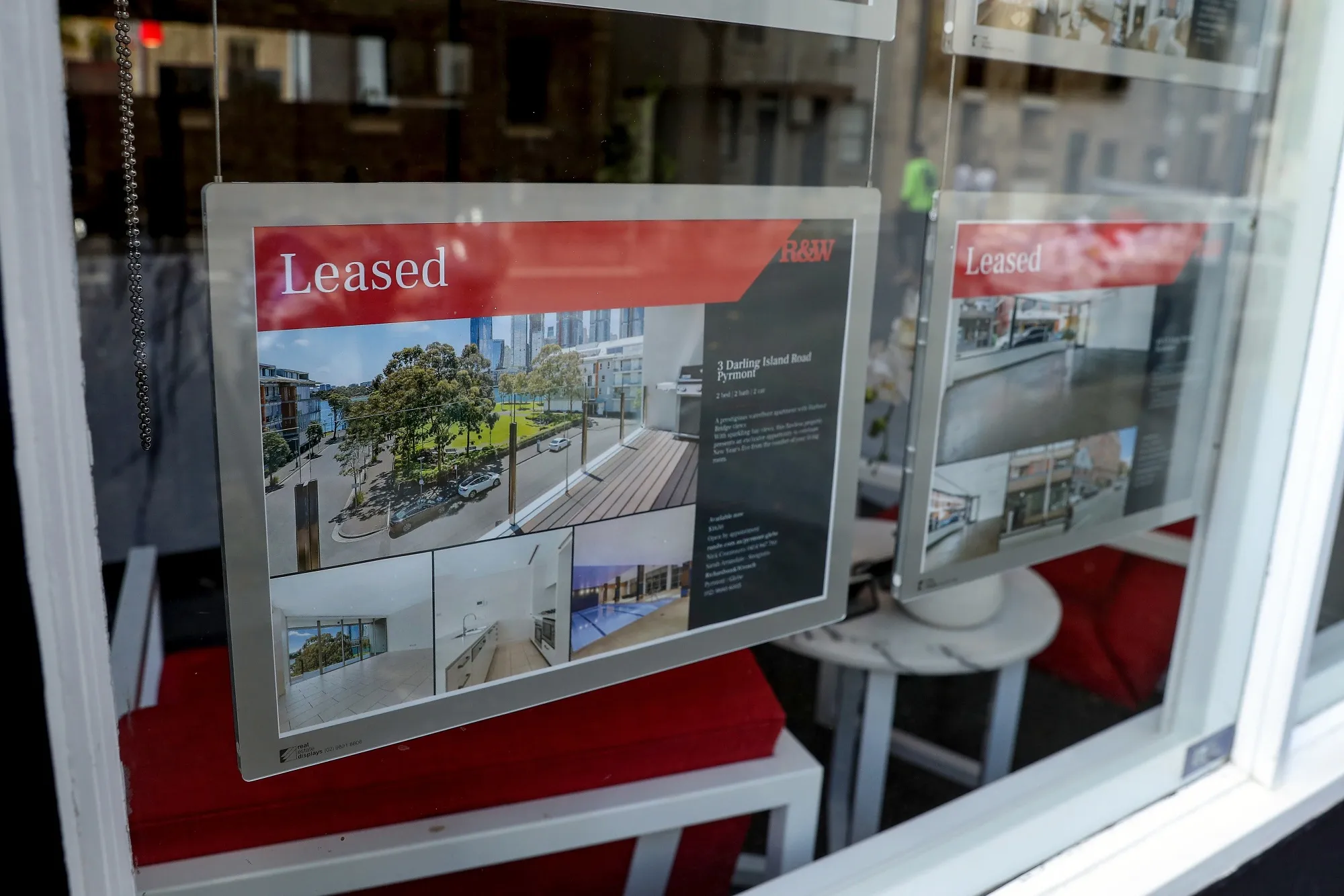 Property listings displayed in the window of a real estate agency in Sydney, Australia.