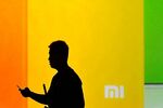 A man looks at his mobile phone as he walks past a screen during the launch of the new Xiaomi smartphone and Xiaomi TV in Beijing on Sept. 5, 2013