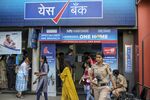 Police officers observe customers standing in line outside a Yes Bank Ltd. branch in Mumbai on March 6.