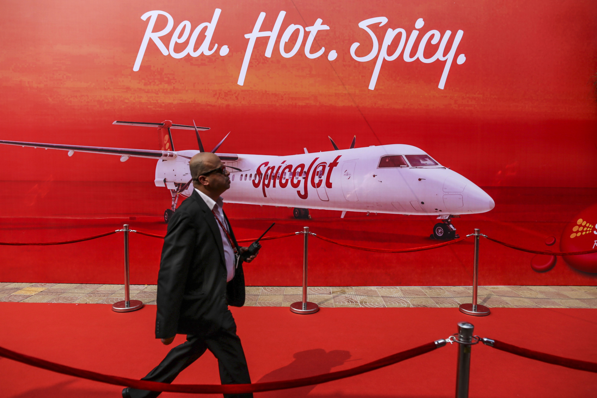 An event staff walks past an advertisement for SpiceJet Ltd. during an event in Mumbai.
