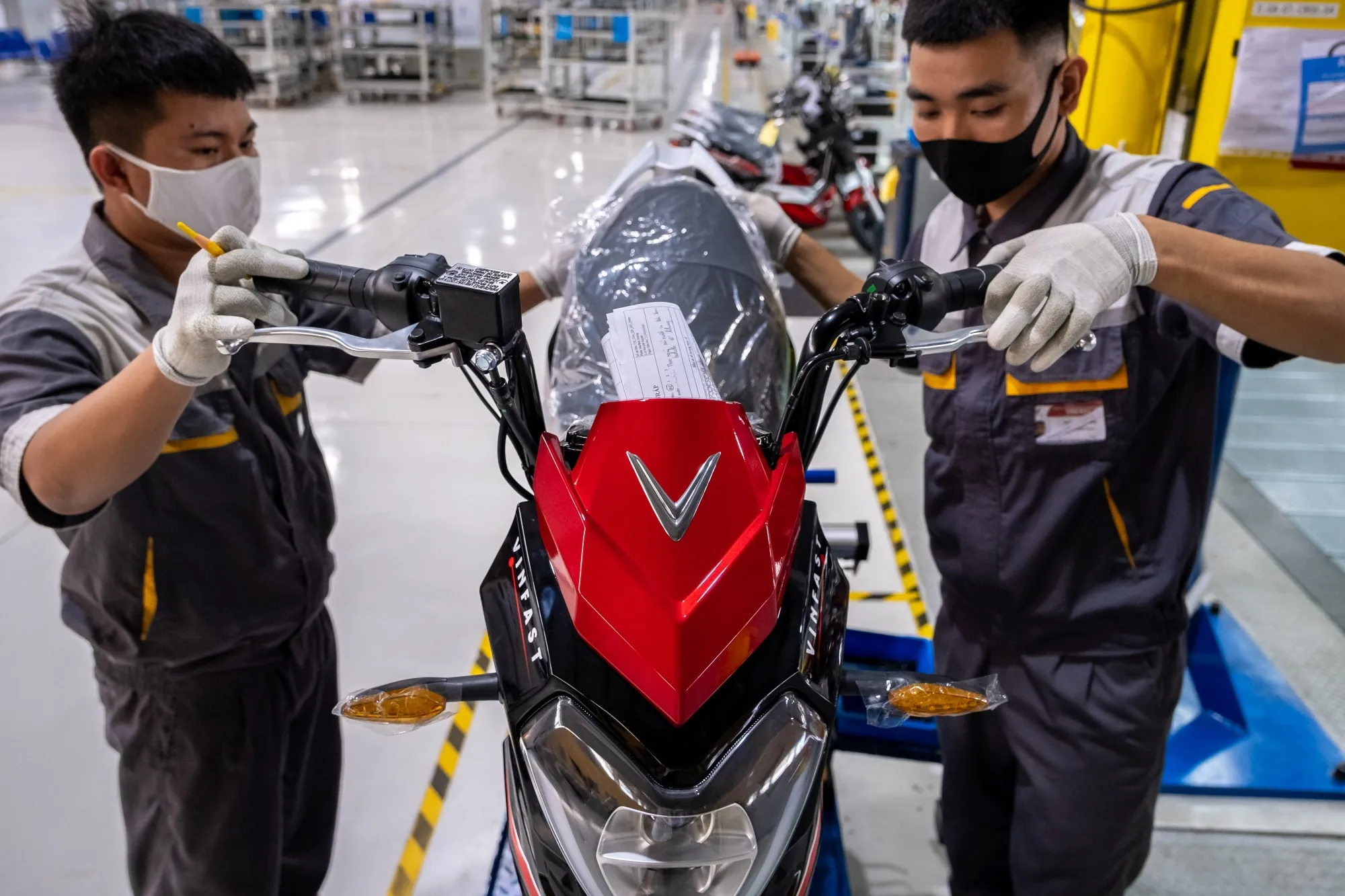 Workers labor on a VinFast Impes electric scooter on the assembly line of the automaker's factory in Haiphong, Vietnam.