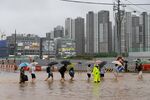Pedestrians are escorted across a flooded road at a junction in Gimpo on&nbsp;Aug. 9.