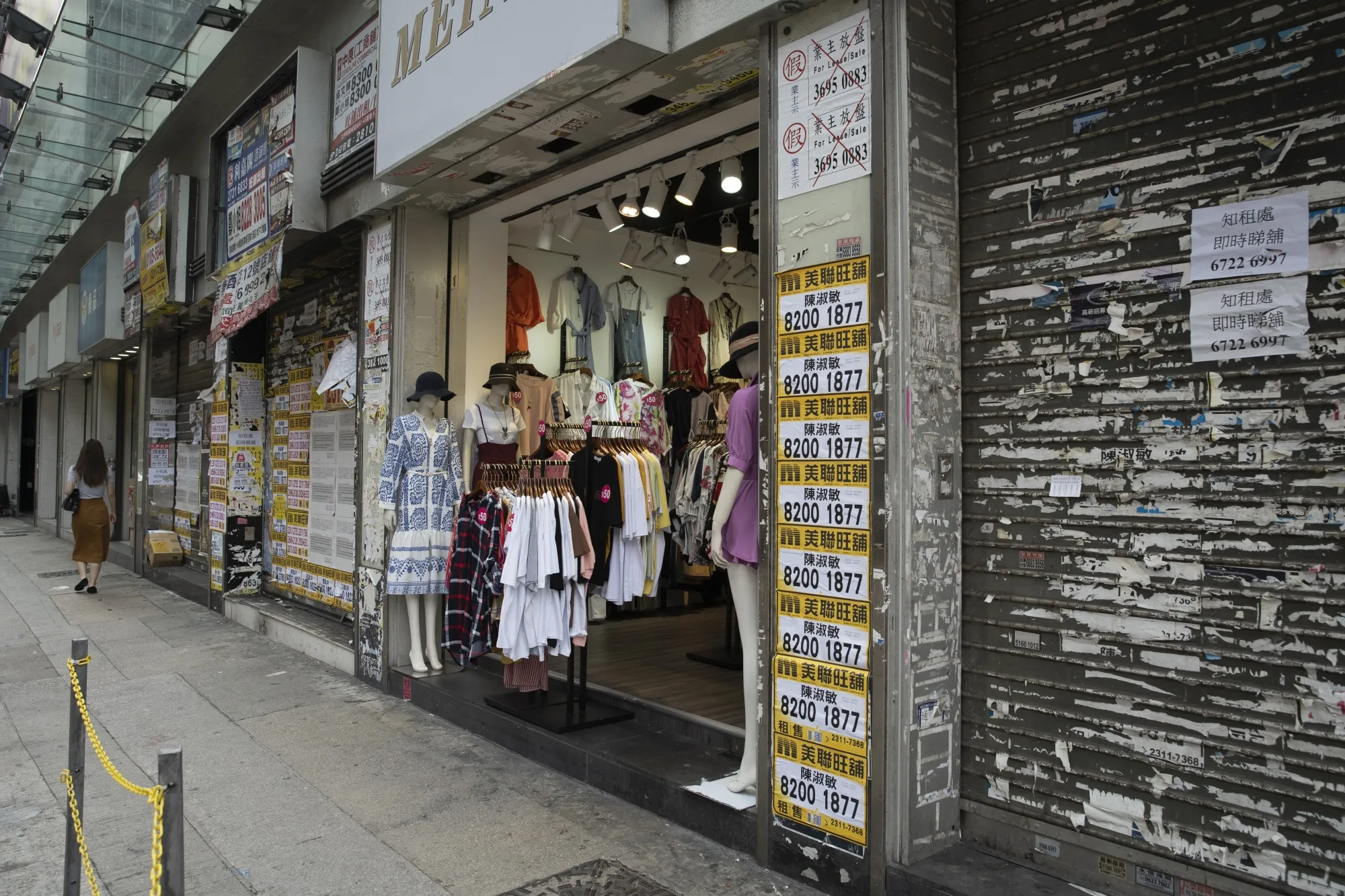 A clothing store stands between shuttered retail spaces covered in rental advertisements in the Tsim Sha Tsui district in Hong Kong on&nbsp;April 21, 2020.&nbsp;