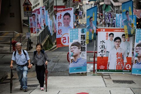 A couple walk past campaign banners during the Legislative Council election in Hong Kong on Sept. 4.