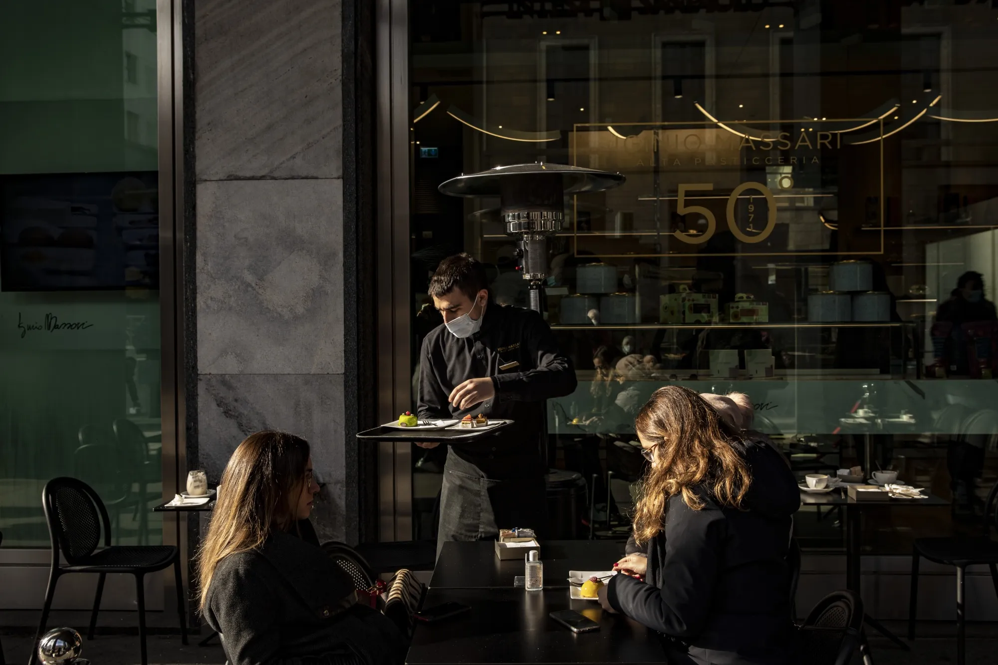 A waiter serves customers&nbsp;outside of a restaurant in Milan, in Nov. 2021.