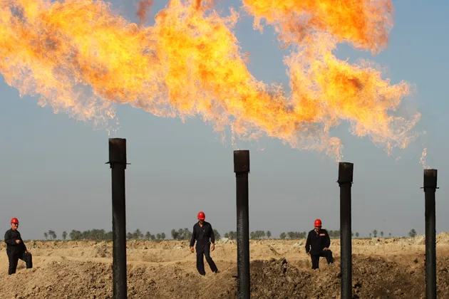 Iraqi workers walk the Halfaya oil field near the southern city of Amarah