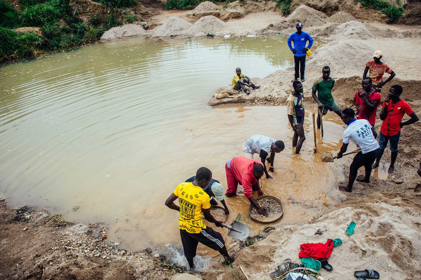 A crew in Kono District sifts through mud and rocks in search of diamonds. The diggers are paid $2.50 a day