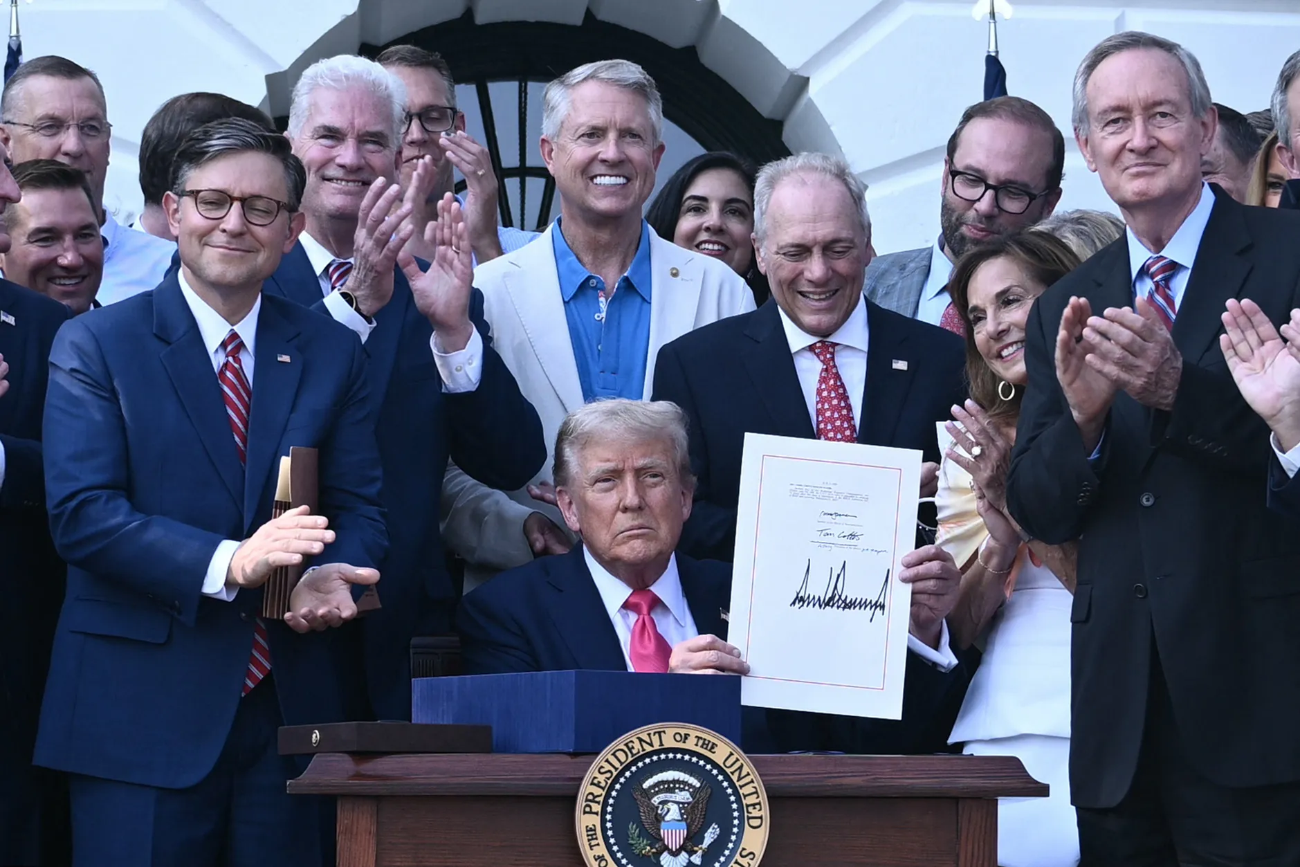 US President Donald Trump (C) shows his signature on the "Big Beautiful Bill Act" at the White House in Washington, DC, on July 4.