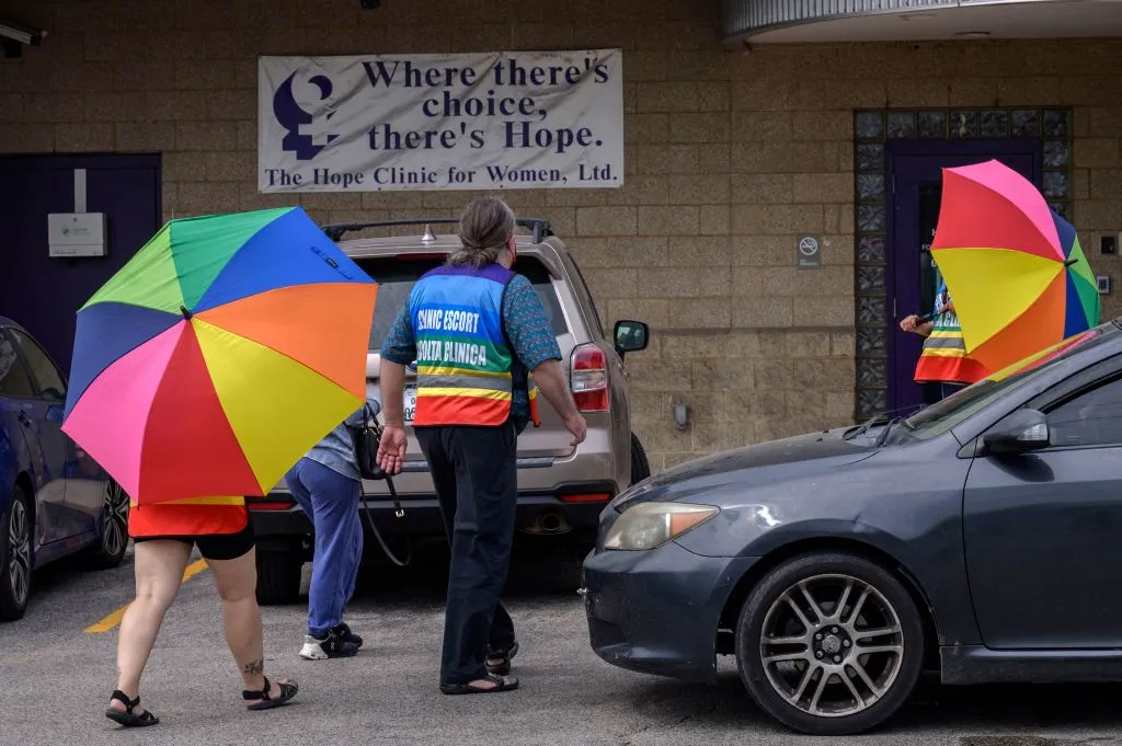 Volunteer clinic escorts shield a patient from anti-abortion demonstrators at the Hope Clinic For Women in Granite City, Illinois, not far from the Missouri border, in June&nbsp;2022.
