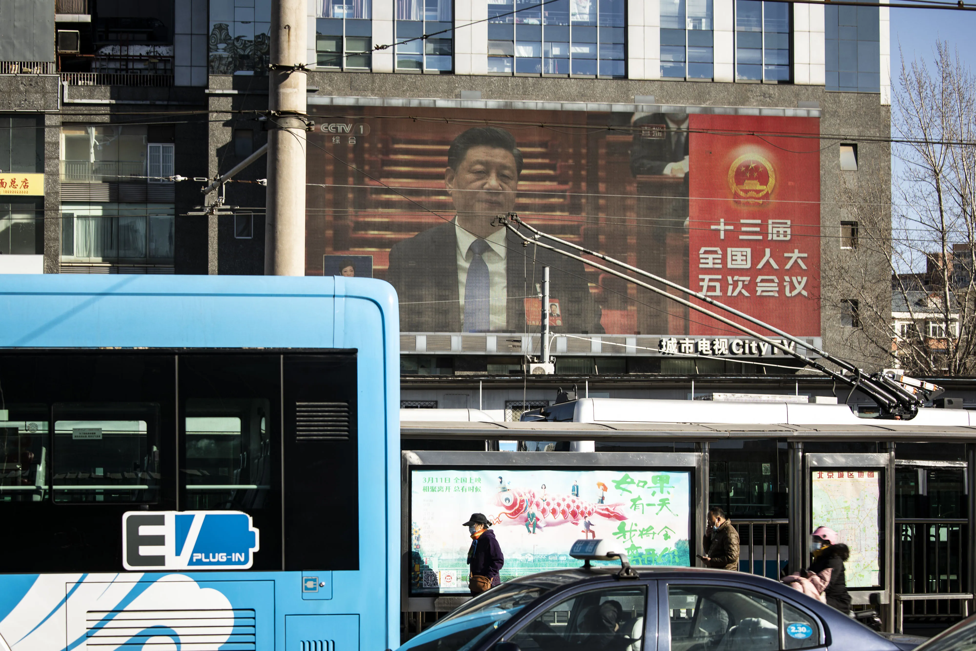 A screen displays a live news broadcast of Chinese President Xi Jinping speaking at the National People's Congress in Beijing, China.