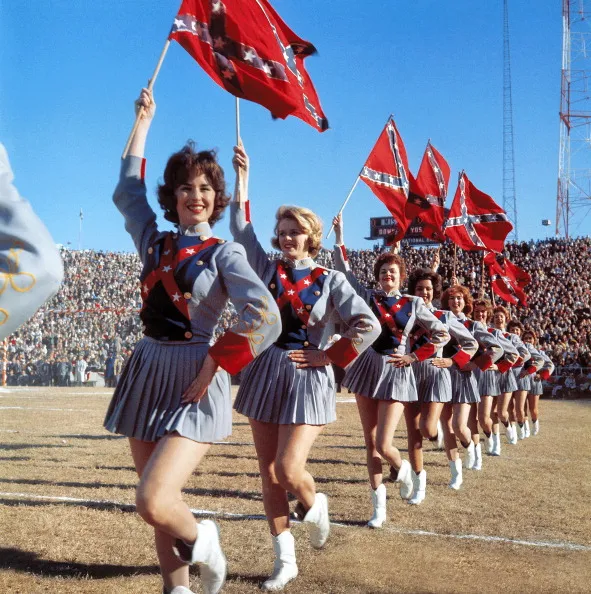 Mississippi cheerleaders Jeffry Whitaker, Dottie Butler, Glynn McPherson, Melinda Stewart, and Linda White in action with Confederate flags during game vs Texas at Cotton Bowl Stadium. Cover. Dallas, TX 1/1/1962
