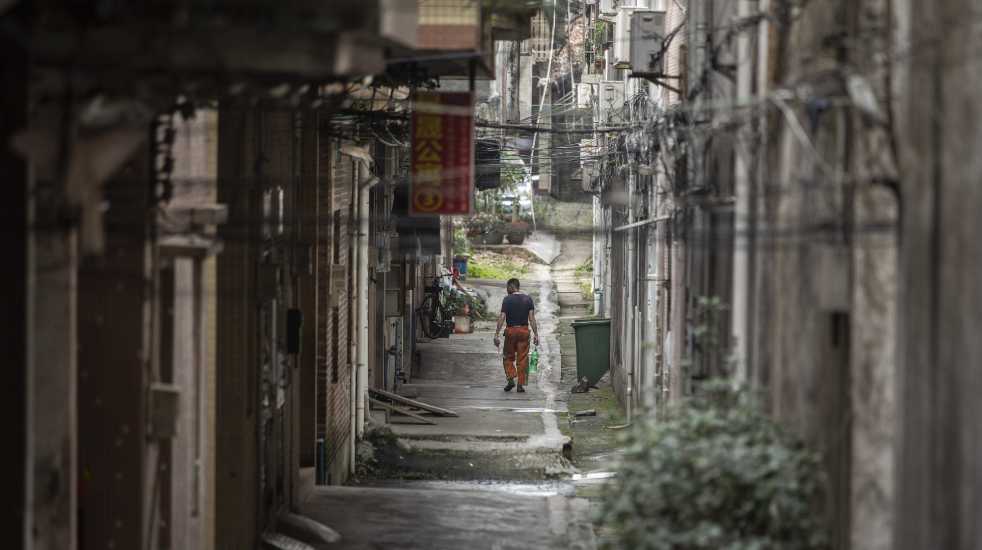A man walks down an alley&nbsp;near a cluster of small factories in Dongguan, China.