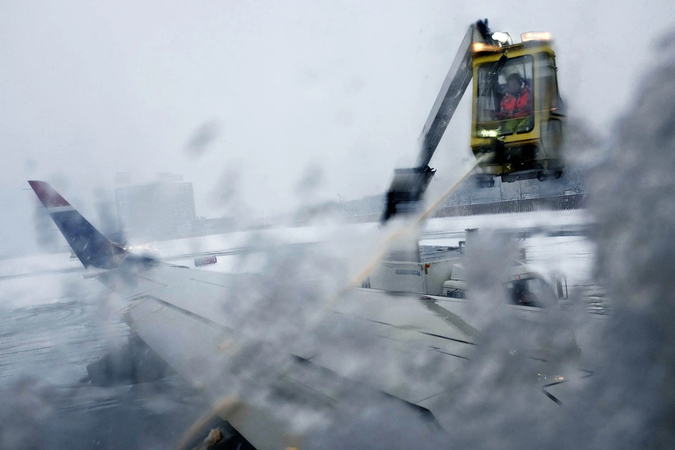 Airport personnel work to de-ice airplanes at Boston's Logan International Airport. Boeing is working on a new non-stick aircraft coatings that may provide a solution to icing.
