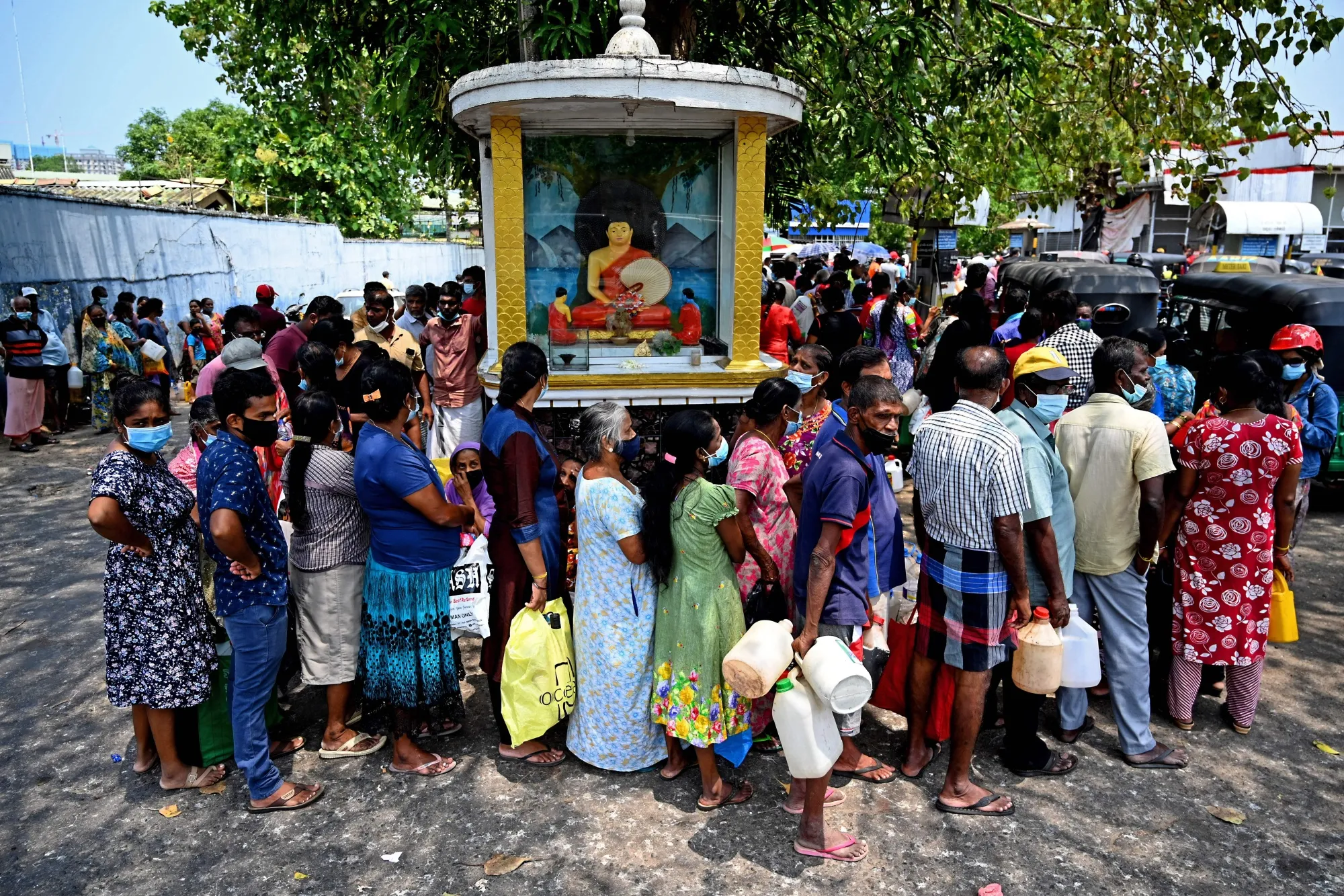 People stand in a line to buy fuel at a gas station in Colombo.