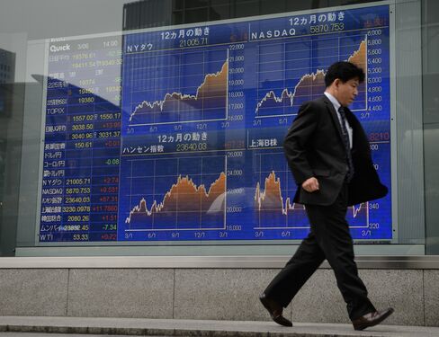 株価ボード前の歩行者